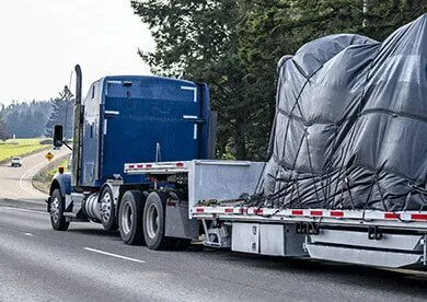 Blue semi truck transporting oversized covered cargo